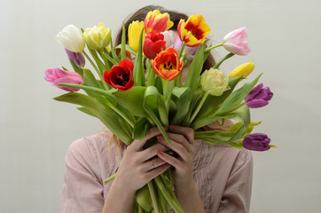 Young charming girl with a bouquet of flowers - multi-colored tulips