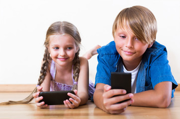 Smiling boy and  girl playing with mobile phones