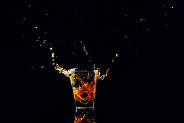 Isolated shot of whiskey with splash on black background, brandy in a glass