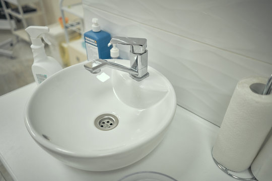 the cosmetologist doctor dials warm water in a transparent bowl to cleanse the skin. After mask for face