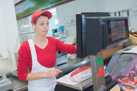 happy mid adult woman weighing meat on scale at butchery