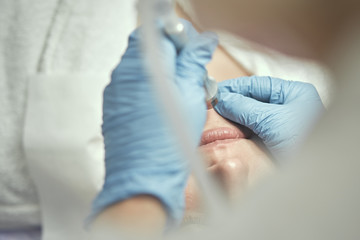 Fototapeta premium Cosmetology and professional skin care. Facial and skin care. The girl is doing Non-injection mesotherapy. The cosmetologist makes the procedure. 
