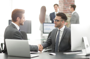 Successful managers shaking hands after closing deal in office