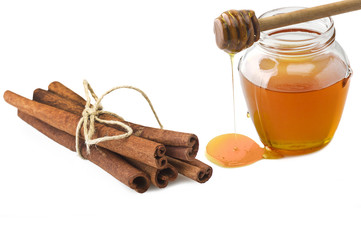 Glass jar of honey with cinnamon sticks on a white
