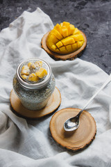 Chia pudding with yellow mango pieces on background of white linen cloth. Vegan healthy diet concept.