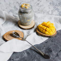 Chia pudding with yellow mango pieces on background of white linen cloth. Vegan healthy diet concept.
