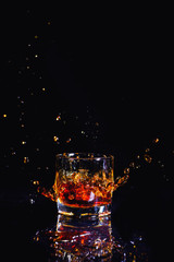 Isolated shot of whiskey with splash on black background, brandy in a glass