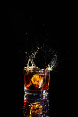 Isolated shot of whiskey with splash on black background, brandy in a glass