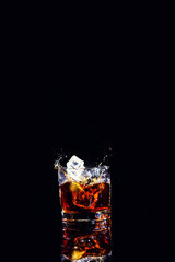 Isolated shot of whiskey with splash on black background, brandy in a glass