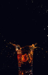 Isolated shot of whiskey with splash on black background, brandy in a glass