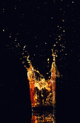 Fototapeta na wymiar Isolated shot of whiskey with splash on black background, brandy in a glass