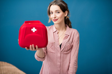 Portrait of a woman with first aid kit on the blue wall background