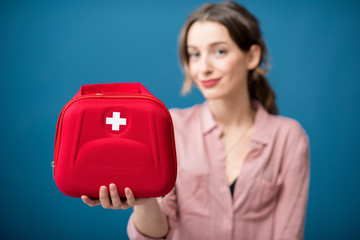 Portrait of a woman with first aid kit on the blue wall background