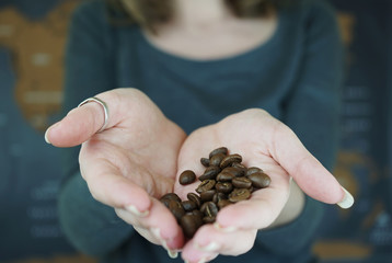 Granos de caf&eacute; tostado de importaci&oacute;n en la mano de una mujer 