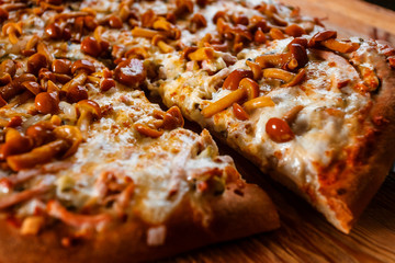 Hot pizza slice with melting cheese on a rustic wooden table.