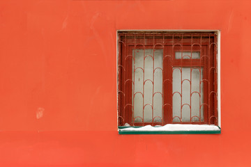 Obraz premium Old window with bars on the red wall