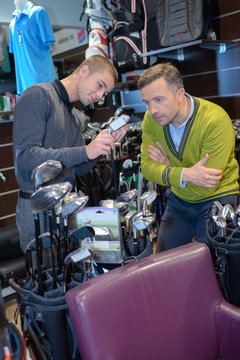 Men examining golf clubs in store