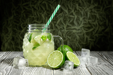Lemonade in a glass jar with slice of lime and ice cubes