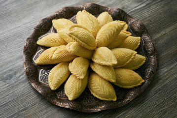 Novruz tray with traditional Azerbaijan pastries shekerbura on wooden table background, top view