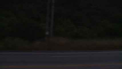A car travels along a street at night in Los Angeles, California as seen through the side window.