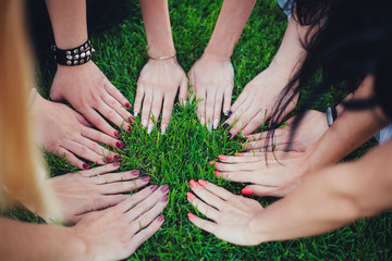 Women friendship. Hands of girls on a green grass, top view. Teamwork, support and partnership.