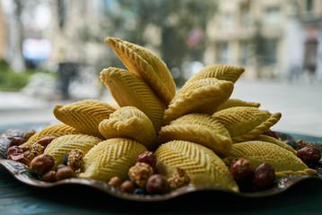 Traditional Azerbaijan pastries shekerbura for Novruz spring equinox celebration on tray on wooden table, close-up