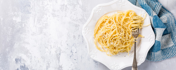 Cacio e Pepe - pasta spaghetti with pecorino cheese and pepper. Healthy italian traditional food concept with copy space. Overhead shot, top view. Banner.