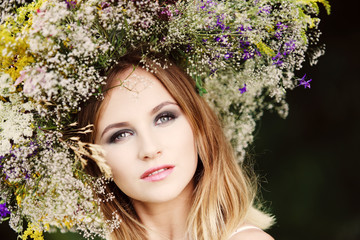 A blonde girl in a wreath of wildflowers.