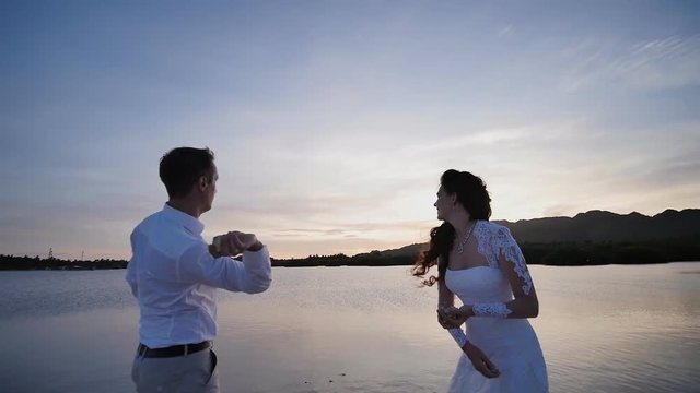 The bride and the groom throw stones into the water together. Sunset. Tropical ocean coast. Philippines. Shooting in motion.