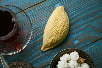 Traditional Azerbaijan sweet pastry shekerbura with nuts and honey and glass of black tea on wooden table background, close up. Delicious dessert Shekerbura baked during the spring holiday Novruz.