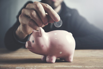 Man putting coin in piggy bank.