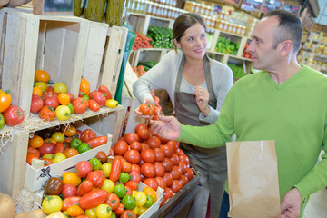 Customer buying tomatoes from greengrocer