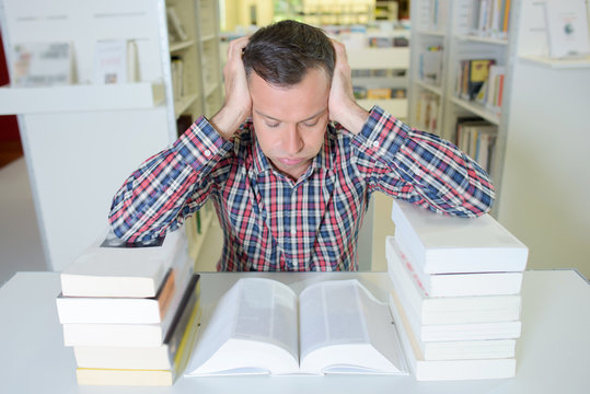 Frusrated man leaning on two piles of books