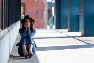 beautiful girl in a hat sending an air kiss. portrait of pretty woman sitting on the ground. Copy space for your text