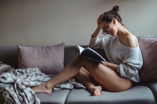 Sexy girl smiling and  reading book on the sofa