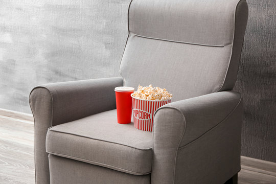 Comfortable armchair with popcorn and drink indoors. Home cinema