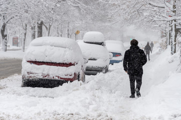 City street and cars covered in snow during winter storm in Montreal, Canada