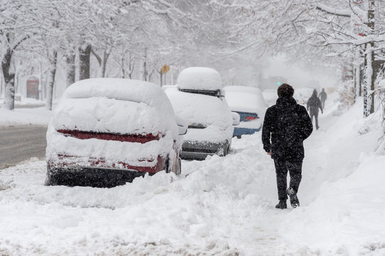 City street and cars covered in snow during winter storm in Montreal, Canada