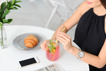 Obraz na płótnie Canvas Young woman with mason jar of pink lemonade in cafe