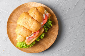 Tasty croissant sandwich on wooden plate