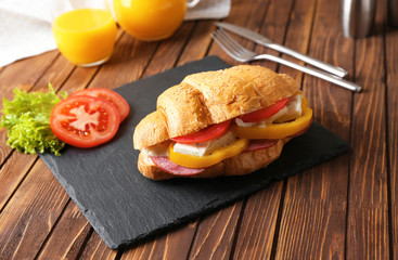Tasty croissant sandwich on slate plate