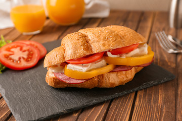 Tasty croissant sandwich on slate plate