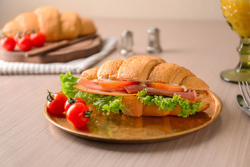 Plate with tasty croissant sandwich on table