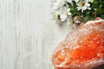 Himalayan salt lamp and flowers on wooden background