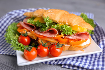Tasty croissant sandwich on plate, closeup