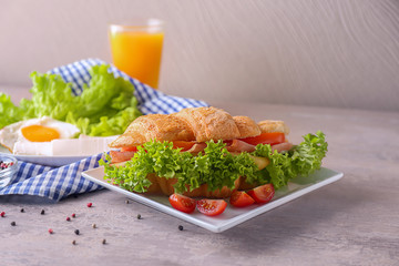Plate with tasty croissant sandwich on table