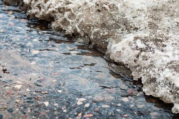Water flows from the melting snow flowing along the asphalt. Spring melting snow.
