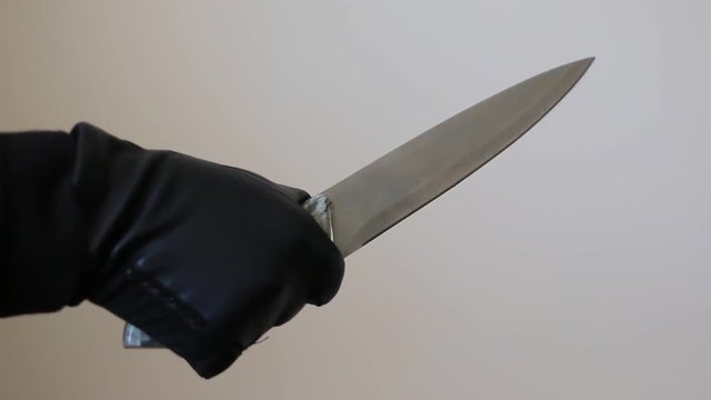 hand in leather gloves holding a big knife