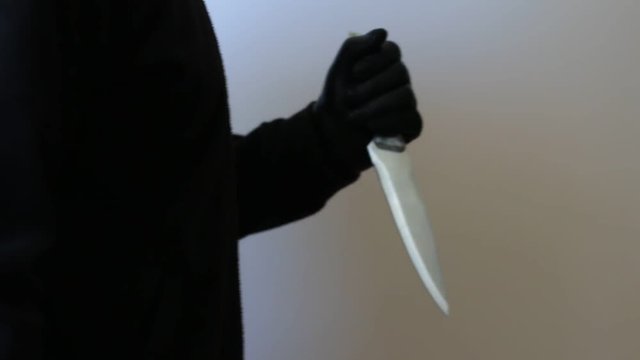 Killer in leather gloves holding big knife