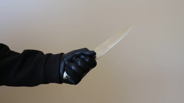hand in leather gloves holding a big knife